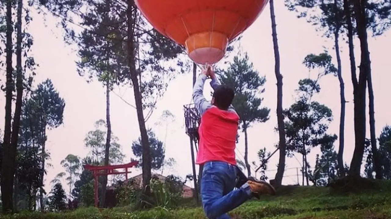 Salah satu pengunjung tengah menikmati jepretan foto tiga dimensi berlatarkan hutan pinus dan balon raksasa di Kamojang Ecopark Garut