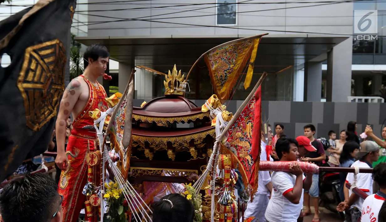 Peserta atraksi Tatung menusuk pipinya dengan besi saat arak-arakan perayaan Cap Go Meh di kawasan Petojo, Jakarta, Selasa (19/2). Seorang Tatung memiliki sejumlah pantangan sebelum beraksi. (Liputan6.com/Angga Yuniar)