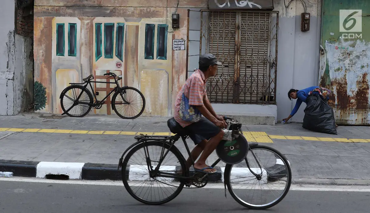 Pengendara sepeda melintas di depan Kampung Tematik Sketsa di kawasan Penjaringan, Jakarta Utara, Rabu (1/7). Sketsa-sketsa yang menghiasi kawasan tersebut dibuat dalam rangka menyambut Asian Games XVIII Tahun 2018. (Liputan6.com/Immanuel Antonius)