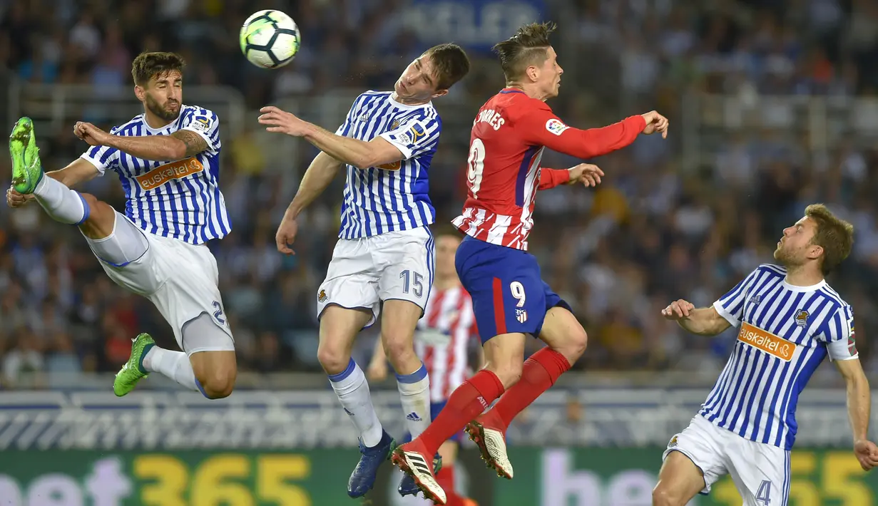 Striker Atletico Madrid, Fernando Torres, duel udara dengan bek Real Sociedad, Aritz Elustondo, pada laga La Liga di Stadion Municipal de Anoeta, Kamis (19/4/2018). Real Sociedad menang 3-0 atas Atletico Madrid. (AFP/Ander Gillenea)