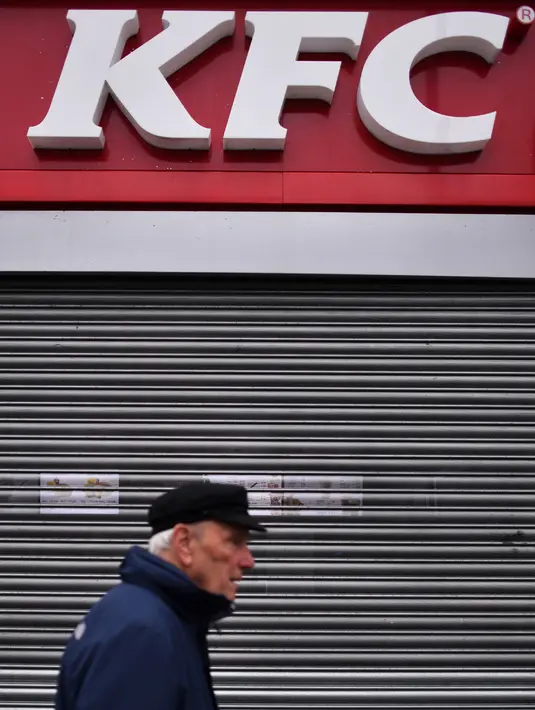 Pejalan kaki melewati sebuah gerai makanan cepat saji KFC yang tutup sementara di London, Inggris, Senin (19/2). Sejumlah pelanggan KFC pun mengungkapkan kekecewaannya di media sosial. (BEN STANSALL/AFP)