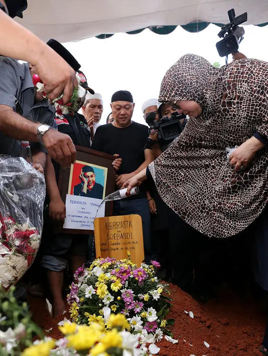 Sang istri, Utami terlihat menyiramkan air pada tempat peristirahatan terakhir suaminya. (Galih W Satria/Bintang.com)