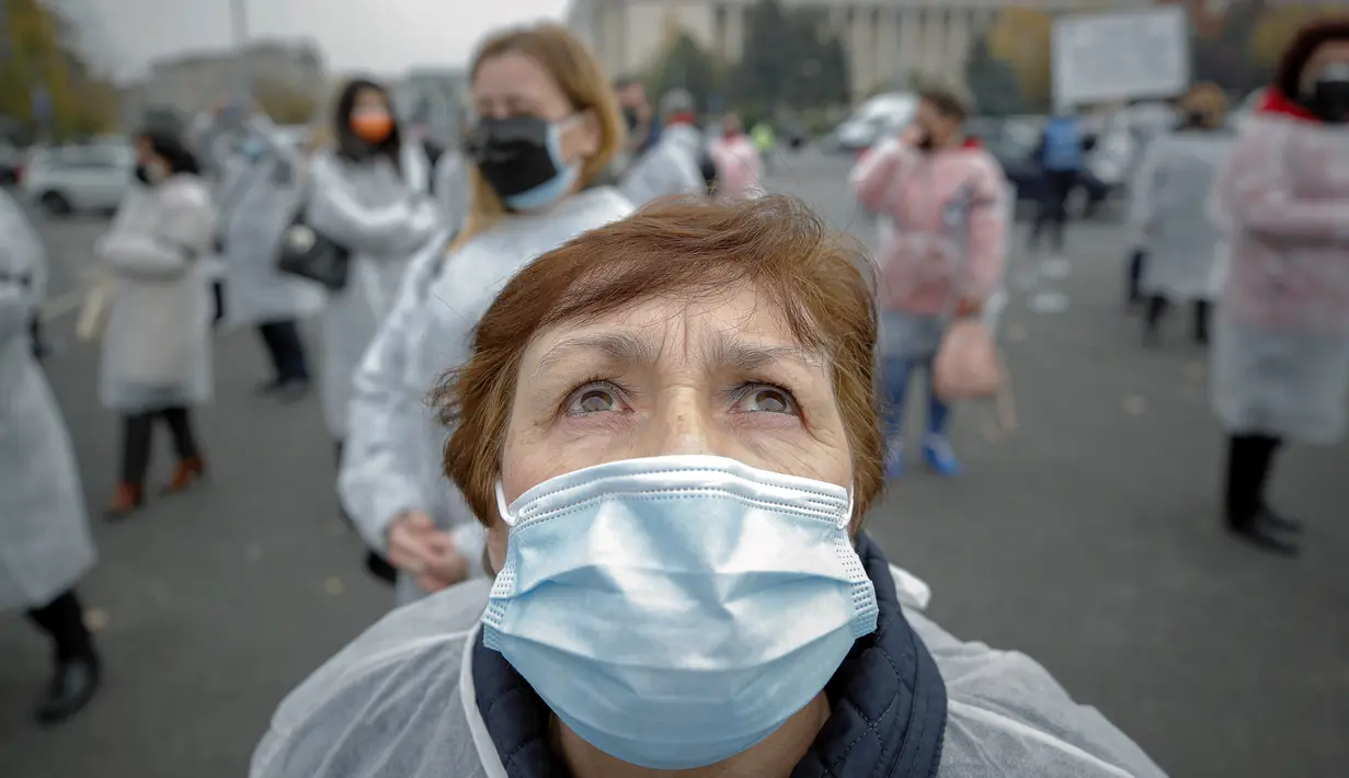 Seorang pekerja medis yang mengenakan masker melihat ke atas setelah melepaskan balon hitam di Bucharest, Rumania, Selasa (17/11/2020). Aksi tersebut untuk mengenang pasien COVID-19 yang tewas dalam kebakaran di IGD  sakit di Piatra Neamt, Rumania pada 14 November 2020 lalu. (AP Photo/Vadim Ghirda)