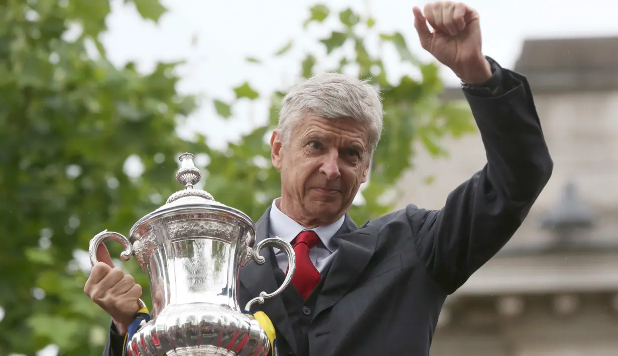 Pelatih Arsenal, Arsene Wenger memegang piala yang diraihnya dalam ajang Piala FA, saat melakukan parade keliling kota di London, Inggris, (31/5/2015). Ini merupakan kali ke 12 bagi Arsenal menjuarai Piala FA. (REUTERS/Neil Hall)