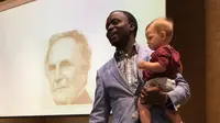 Profesor Henry Musoma menggendong anak Ashton Robinson saat kelas sedang berlangsung (facebook.com/ashton.robinson)
