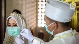 Pasangan pengantin menggunakan masker sebelum melaksanakan prosesi akad nikah di KUA Jagakarsa, Jakarta, Sabtu (6/6/2020). Pada masa penerapan PSBB transisi, pihak KUA tersebut menikahkan sebanyak delapan hingga 10 pasangan pengantin per hari. (Liputan6.com/Faizal Fanani)