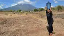 Warga membawa air melintasi perkebunan di Kec Kubu, Kab Karangasem, Bali, Selasa, (26/9). Lebih dari 57.000 orang telah mengungsi pasca peningkatan status Gunung Agung di Bali. (AP Photo / Firdia Lisnawati)