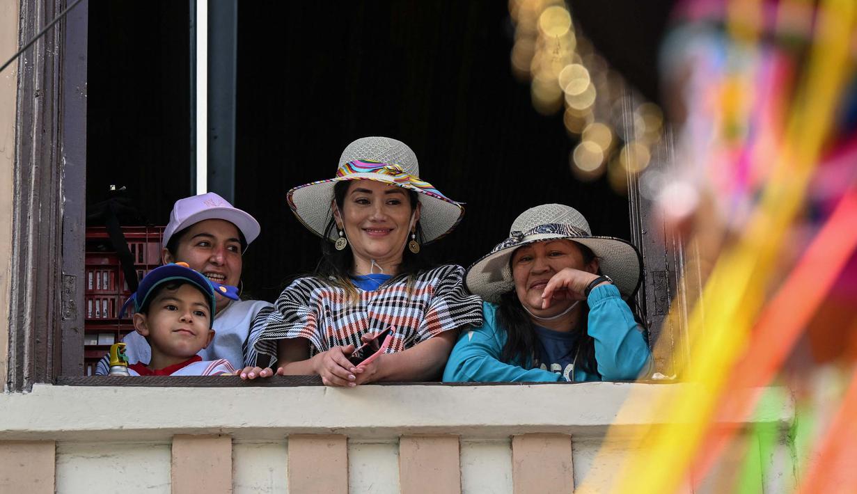Orang-orang menyaksikan para peserta yang bergembira saat mengambil bagian dalam parade "Nyanyian untuk Bumi" selama Karnaval Kulit Hitam dan Kulit Putih di Pasto, Kolombia pada tanggal 3 Januari 2024. (JOAQUIN SARMIENTO/AFP)
