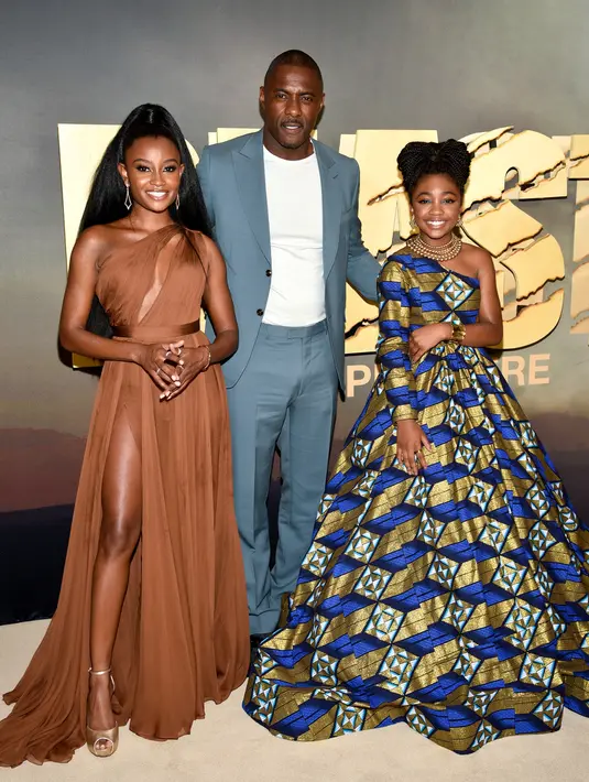 <p>Aktor Idris Elba (tengah) bersama aktris Iyana Halley (kiri) dan Leah Jeffries (kanan) berpose bersama saat menghadiri pemutaran perdana film Beast di Museum of Modern Art, New York, Amerika Serikat, 8 Agustus 2022. Iyana tampil glamor dalam balutan gaun single-shoulder berwarna cokelat dengan potongan diagonal dan belahan tinggi pada roknya, sementara Leah tampil elegan dalam balutan gaun single-shoulder bermotif biru-emas dengan rok yang bervolume. (Photo by Evan Agostini/Invision/AP)</p>