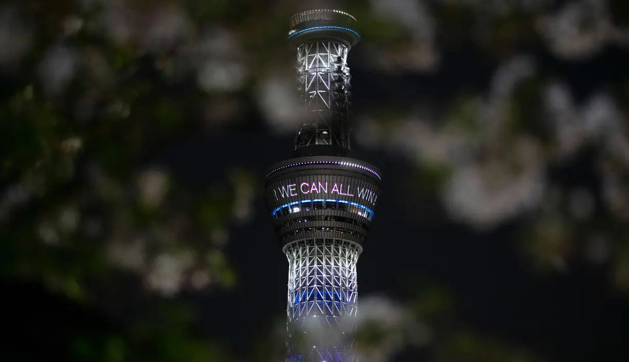Tokyo Skytree menampilkan pesan bertuliskan "Bersama Kita Semua Bisa Menang" di Tokyo, Senin (6/4/2020). Ungkapan dukungan dan pesan harapan tersebut muncul di tengah merebaknya pandemi virus corona Covid-19. (AP Photo/Jae C. Hong)