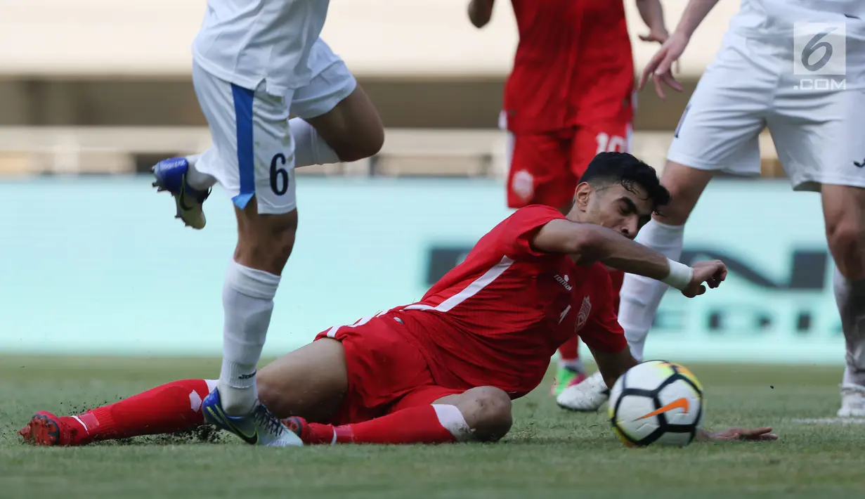 Pemain belakang Bahrain, Husain Sabba terjatuh saat menahan serangan pemain Uzbekistan saat laga PSSI Anniversary Cup 2018 di Stadion Pakansari, Kab Bogor, Senin (30/4). Laga berakhir imbang 3-3. (Liputan6.com/Helmi Fithriansyah)