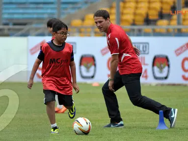 Seorang anak terlihat memainkan bola bersama Michael Owen dalam sesi coaching clinic yang digelar di Stadion GBK Jakarta (Liputan6.com/ Helmi Fithriansyah)