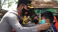 Kapolres Pemalang AKBP Ari Wibowo memakaikan masker ke anak yang tengah berkunjung ke objek wisata. (Foto: Liputan6.com/Humas Polres Pemalang)