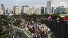 Warga mengisi libur Tahun Baru dengan menikmati pemandangan Kota Jakarta dari Skywalk Senayan Park, Sabtu (1/1/2022). Skywalk Senayan Park kini menjadi salah satu tempat wisata pilihan warga Jakarta lantaran pemandangannya yang instagramable. (Liputan6.com/Johan Tallo)