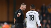 Pemain Manchester United, Casemiro (kanan) diberikan peringatan oleh wasit&nbsp;Robert Jones saatpertandingan lanjutan Liga Inggris 2022/2023 melawan Wolverhampton Wanderers&nbsp;yang berlangsung di&nbsp;Molineux stadium (31/12/2022). (AFP/Adrian Dennis)