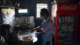 Penjual menyiapkan makanan di tokonya setelah pemadaman listrik di Kolombo, Rabu (2/3/2022). Sri Lanka mengumumkan pemadaman listrik setiap hari selama 7,5 jam, terlama dalam lebih dari seperempat abad, karena krisis valuta asing membuatnya tidak dapat mengimpor minyak. (Ishara S. KODIKARA/AFP)