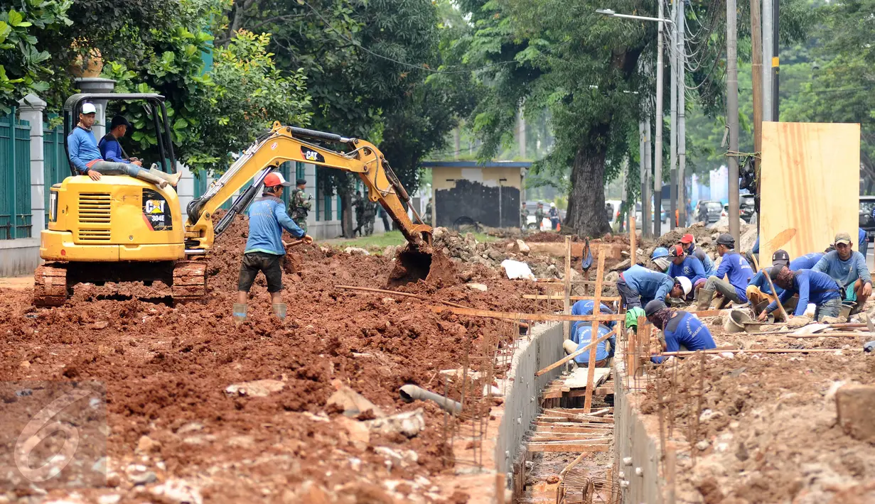 Sejumlah pekerja menyelesaikan pengerjaan saluran air di sekitar jalan Gerbang Pemuda, Jakarta, Senin (6/3). Pembuatan saluran air dan peningkatan pedestrian ini terkait pelaksanaan Asian Games 2018 mendatang. (Liputan6.com/Helmi Fithriansyah)