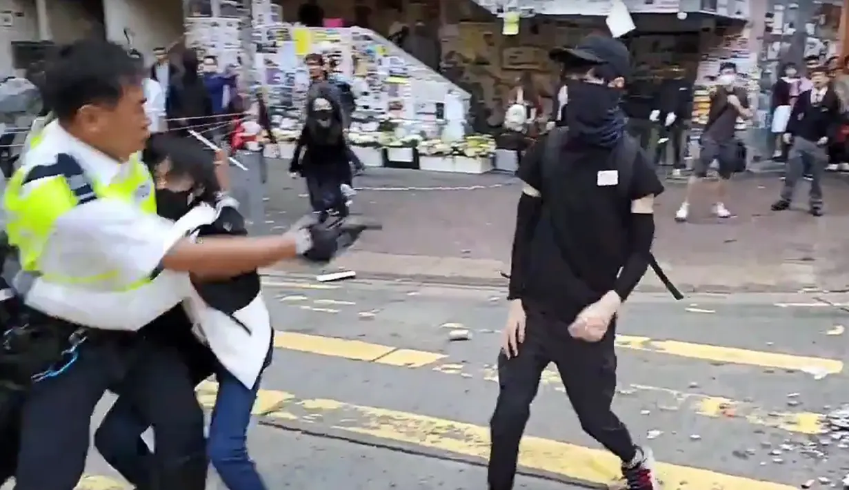 Polisi (kiri) menembak seorang demonstran prodemokrasi (kanan) saat terjadi protes di Distrik Sai Wan Ho, Hong Kong, Senin (11/11/2019). Aksi penembakan yang dilakukan polisi tersebut tersiar secara langsung lewat layanan streaming Facebook. (LAURENT FIEVET/CUPID NEWS/AFP)