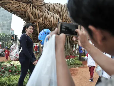 Pengunjung Car Free Day berfoto dengan latar belakang instalasi bambu "Getih Getah" di Bundaran HI, Jakarta, Minggu (19/8). Karya seni Joko Avianto itu langsung diserbu dan menjadi objek foto baru bagi sejumlah masyarakat. (Merdeka.com/ Iqbal S. Nugroho)