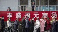 Seorang wanita melihat orang-orang yang berbaris untuk pengujian massal COVID-19 di Beijing, China, Jumat (22/1/2021). Beijing memerintahkan pengujian COVID-19 untuk sekitar dua juta orang menyusul kasus baru. (AP Photo/Mark Schiefelbein)