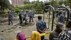 Warga berkumpul dan menyaksikan aktivitas sejumlah personel Angkatan Udara Bangladesh membersihkan puing-puing saat memeriksa lokasi jatuhnya pesawat latih milik Angkatan Udara Bangladesh yang menimpa kompleks sekolah di Dhaka, 22 Juli 2025. (MUNIR UZ ZAMAN/AFP)