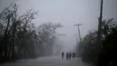 Warga berjalan di bawah tiang listrik setelah Badai Matthew menghantam wilayah Les Cayes di Haiti (4/10). Badai Matthew ini telah mengakibatkan banjir, banyak pohon tumbang dan ratusan rumah warga rusak parah. (REUTERS/Andres Martinez Casares)