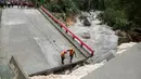 Tim penyelamat Guatemala berdiri di jembatan yang ambruk disebabkan oleh Badai Earl di Menchor de Mencos, Guatemala (4/8). Badai Earl menimbulkan hujan lebat, banjir dan angin kencang di sejumlah negara di Amerika Tengah. (REUTERS/Luis Echeverria)