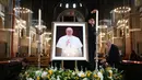 Para staf memasang gambar Paus Fransiskus setelah berita kematiannya di dalam Katedral Metropolitan Darah yang Paling Berharga, yang secara informal dikenal sebagai Katedral Westminster, di pusat kota London pada 21 April 2025. (HENRY NICHOLLS/AFP)