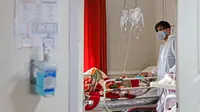 Petugas medis merawat seorang pasien yang terinfeksi virus corona atau COVID-19 di sebuah rumah sakit di Teheran, Iran, Minggu (1/3/2020). Sejauh ini, Iran mencatat ada 1.501 kasus virus corona dengan 66 korban meninggal. (Ali Shirband/Mizan News Agency via AP)