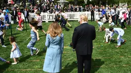 Presiden AS Donald Trump dan Ibu Negara Melania Trump menyaksikan anak-anak menggelindingkan telur paskah di South Lawn Gedung Putih, Washington, Senin (22/4). Acara tahunan itu merupakan bagian dari rangkaian memperingati Paskah yang rutin diselenggarakan Gedung Putih. (Brendan Smialowski/ AFP)