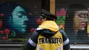 Polisi lalu lintas berdiri di depan toko yang dihiasi mural sebagai bagian dari program pemerintah di Mexico City, 30 Agustus 2017. Mural  sebagai bagian dari upaya pemerintah menghidupkan kembali ruang publik di wilayah kota tua. (ALFREDO ESTRELLA/AFP)