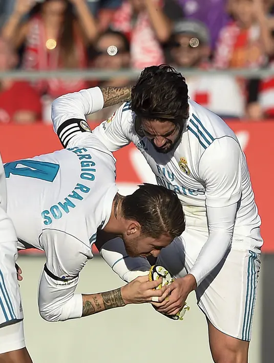 Pemain Real Madrid, Sergio Ramos (tengah) mencium sepatu rekannya Isco saat merayakan gol melawan Girona pada lanjutan La Liga Santander di Municipal de Montilivi stadium, Girona , (29/10/2017). Madrid kalah 1-2. (AFP/Josep Lago)