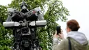 Warga mengabadikan robot yang mirip karakter film Transformers dengan ponselnya di Zagreb, Kroasia (18/4). Robot ini dibuat dengan memanfaatkan bangkai mobil rusak akibat kecelakaan. (REUTERS/Antonio Bronic)