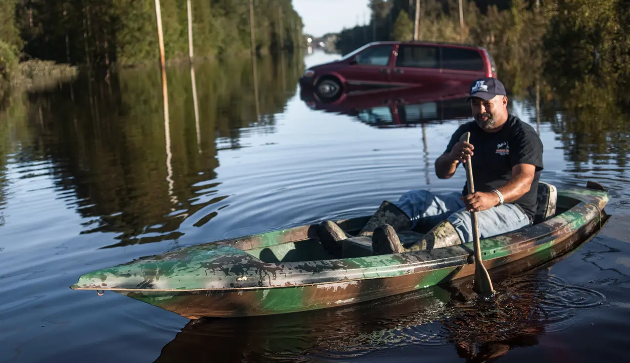 Eric Locklear menggunakan kano untuk beraktivitas di tengah banjir yang merendam wilayah Lumberton di Carolina Utara, AS, 12 Oktober 2016. Banjir akibat badai Matthew tersebut merendam kota berpenduduk 21.000 orang itu. (Sean Rayford/Getty Images/AFP)