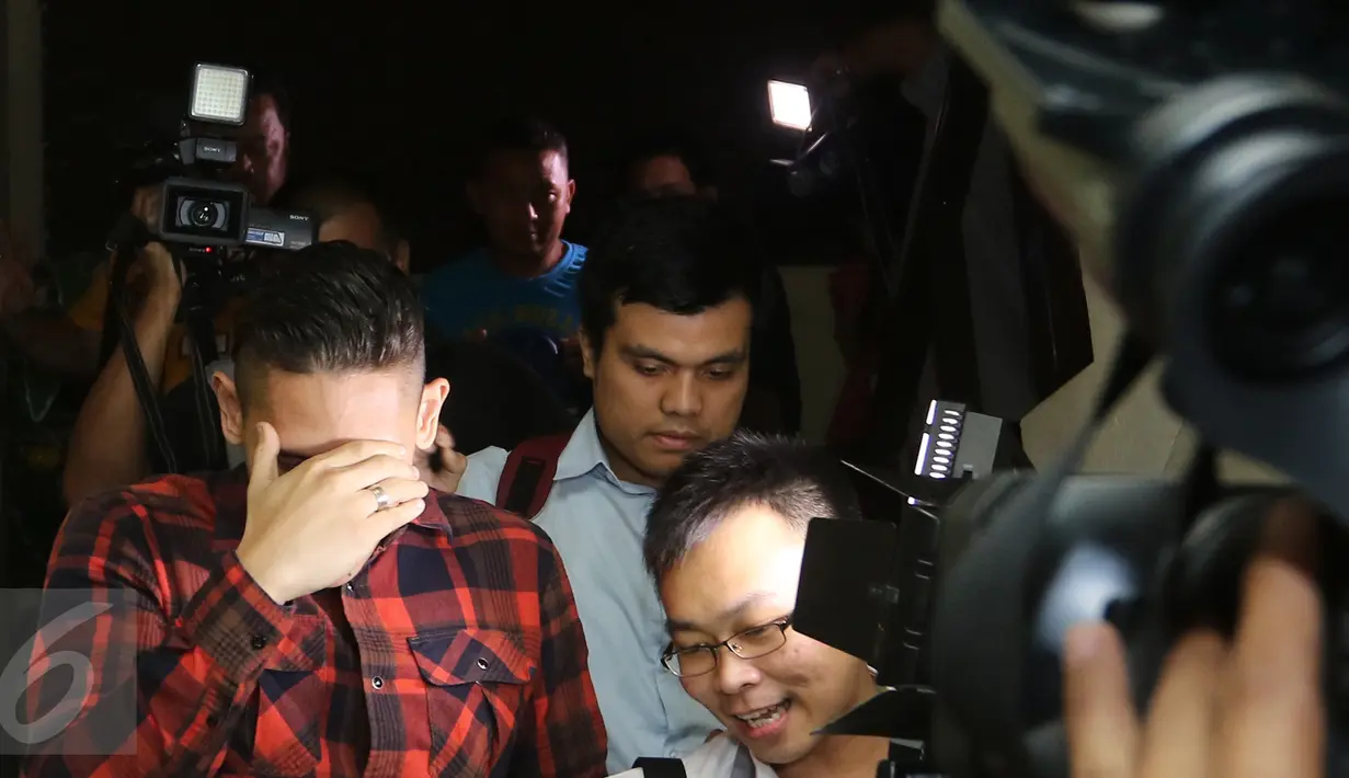 Aktor dan presenter Ganindra Bimo menutup mukanya saat para wartawan menghampirinya usai menjalani pemeriksaan di polsek Jagakarsa, Jakarta, Kamis (18/02/2016) .(Liputan6.com/Herman Zakharia)
