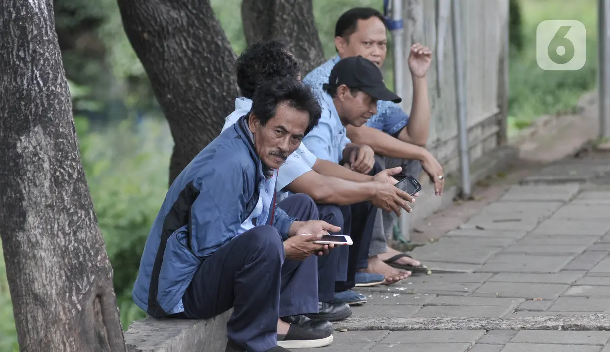 Sopir taksi berbincang tanpa mengenakan masker saat menunggu penumpang di kawasan Cawang, Jakarta, Rabu (8/4/2020). Organisasi Kesehatan Dunia (WHO) telah merekomendasikan agar menggunakan masker saat berada di tempat umum demi memutus mata rantai penyebaran virus Corona. (merdeka.com/Iqbal Nugroho)