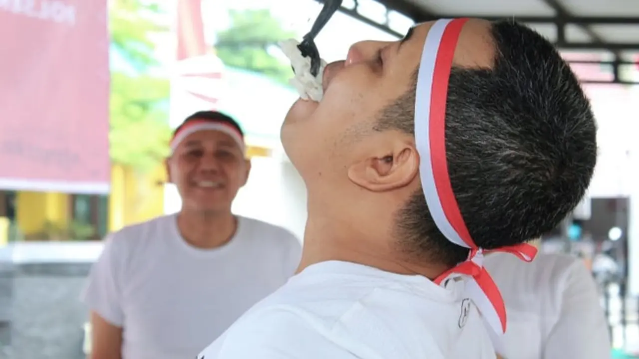 Personel Polsek Lima Puluh mengikuti lomba makan kerupuk menyambut Hari Kemerdekaan Indonesia.