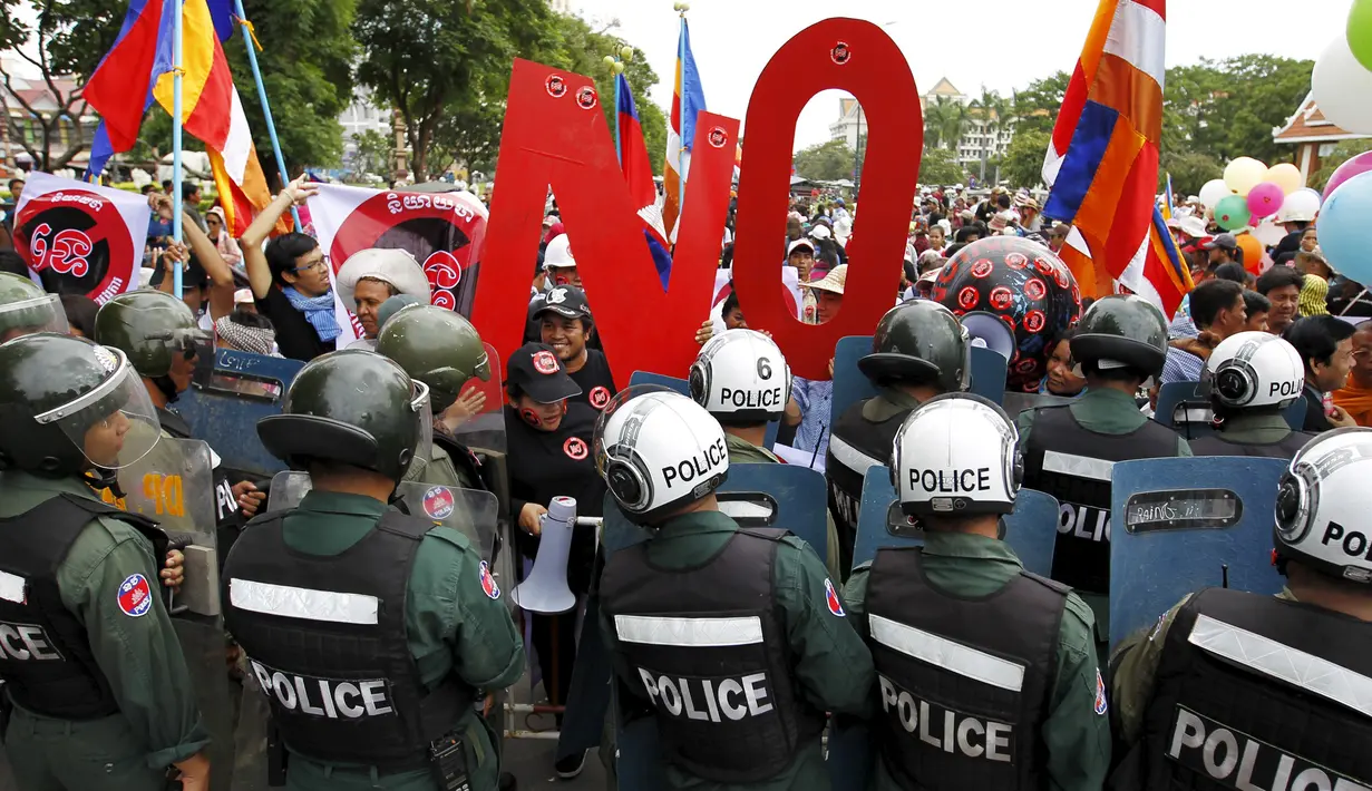 Petugas kepolisian menghalang para pengunjuk rasa di Phnom Penh, Kamboja, Senin (13/7/2015). Pengunjuk rasa berpandangan aturan ini dapat memberangus pihak oposisi. (REUTERS/Samrang Pring)