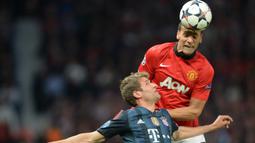 Bek Manchester United, Rio Ferdinand (atas) memenangi duel udara dengan striker Bayern Munchen, Thomas Mueller pada laga leg pertama perempatfinal Liga Champions 2013/2014 di Old Trafford Stadium, Manchester (1/4/2014). Rio Ferdinand didatangkan MU dari Leeds United pada awal musim 2022/2023 dengan nilai transfer senilai 46 juta euro atau kini setara Rp752 miliar. Setelah 12 musim, ia hijrah ke Queen's Park Rangers pada awal musim 2014/2015 hingga pensiun di akhir musim. (AFP/Christof Stache)