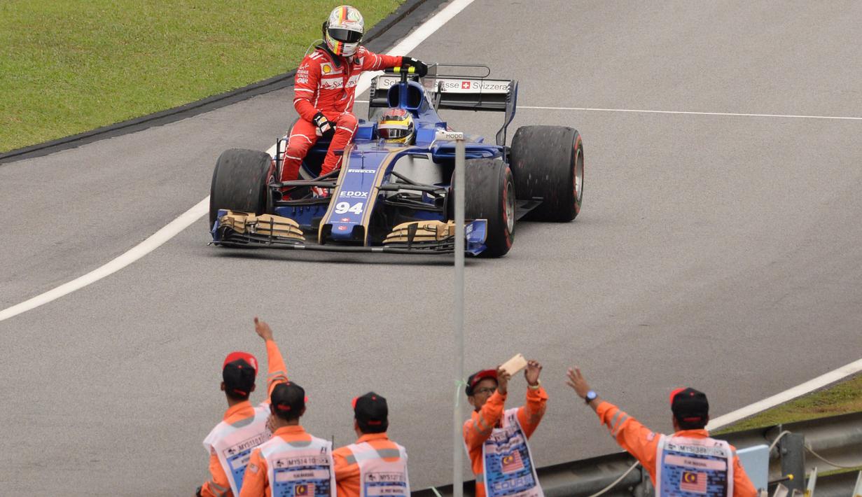 Pebalap Ferrari, Sebastian Vettel terpaksa menumpang mobil rekan senegaranya, Pascal Wehrlein setelah terlibat kecelakaan pada balapan Formula One Malaysia Grand Prix, Sepang, (01/10/2017). Vettel akhirnya finis pada posisi keempat. (AFP/Roslan Rahman)