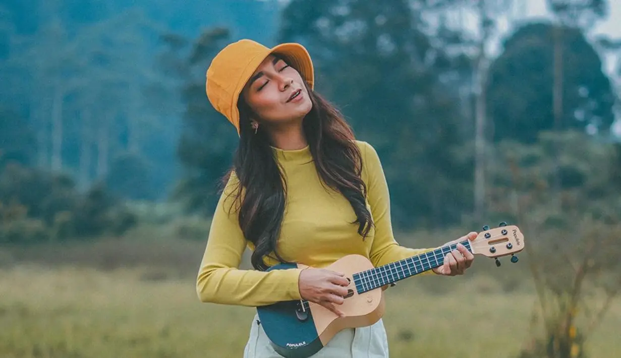 Beberapa momen, Dinda Kirana memang terlihat begitu senang memainkan alat musik ukulele. Dengan gaya santainya di alam bebas, Dinda sangat menikmati momen-momen bersenandung dengan ukulelenya. (Liputan6.com/IG/@dindakirana.s)