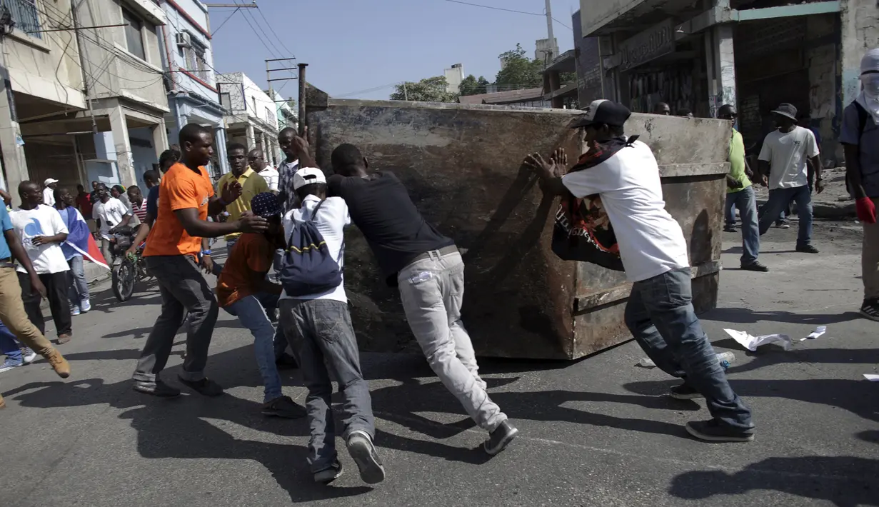 Pengunjuk rasa merusak tempat sampah saat demo pemilu di Port-au-Prince, Haiti (18/1). Warga menuduh pemilu presiden Haiti berjalan curang yang menyebabkan kemarahan warga hingga membakar fasilitas umum. (REUTERS/Andres Martinez Casares)