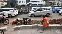 Aktivitas pekerja saat menyelesaikan proyek revitalisasi trotoar di Jalan Tebet Raya, Jakarta, Selasa (5/11/2019). Adanya proyek revitalisasi trotoar di sepanjang Jalan Tebet Raya mengakibatkan kemacetan di kawasan tersebut semakin parah, terlebih saat jam sibuk. (merdeka.com/Iqbal Nugroho)