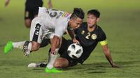 Pemain Bali United, Fahmi Al-Ayyubi, terjatuh saat berebut bola dengan bek Timnas Indonesia, Andy Setyo, pada laga uji coba di Stadion Madya, Minggu (7/3/2021). (Bola.com/ Ikhwan Yanuar Harun)