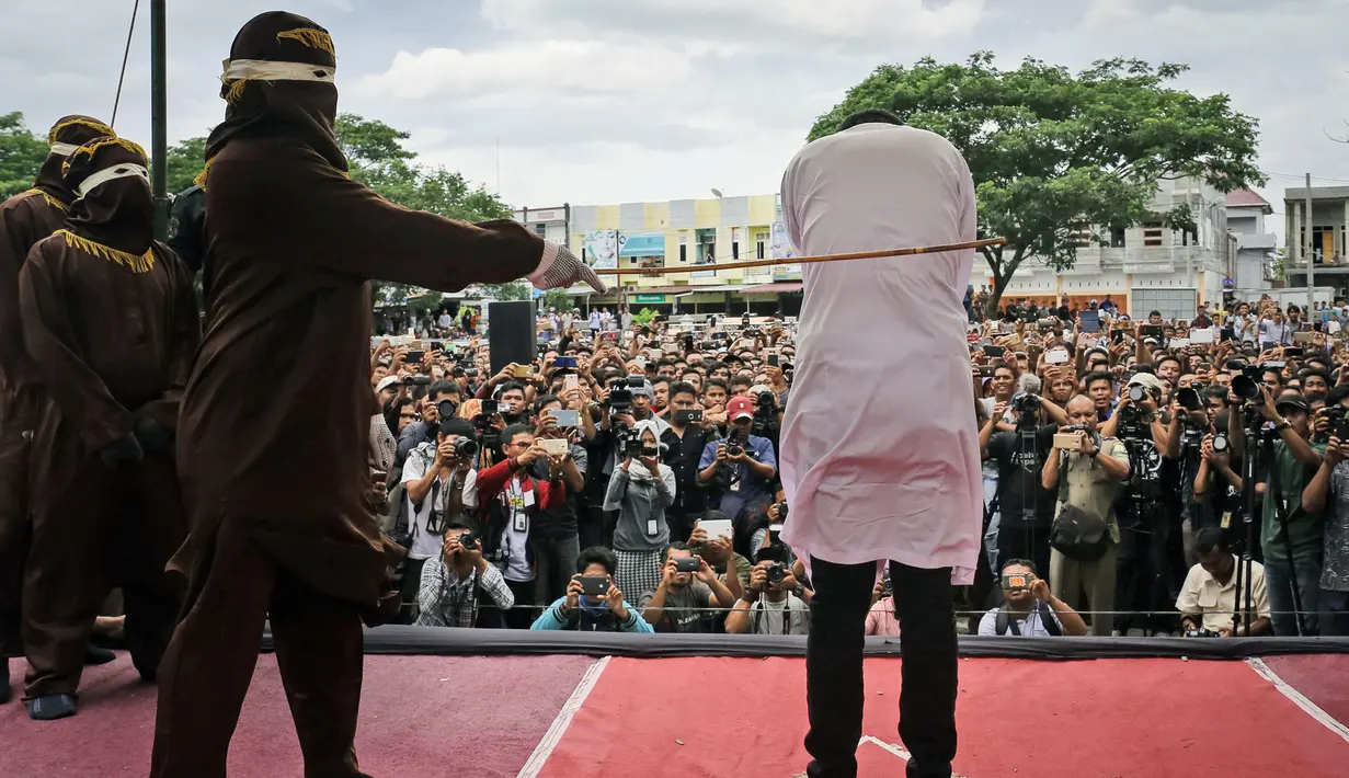 Petugas menyabetkan rotan ke punggung seorang terpidana kasus liwath alias gay di Banda Aceh, Indonesia, (23/5). Eksekusi hukuman cambuk ini digelar terbuka di hadapan publik. (AP Photo / Heri Juanda, File)
