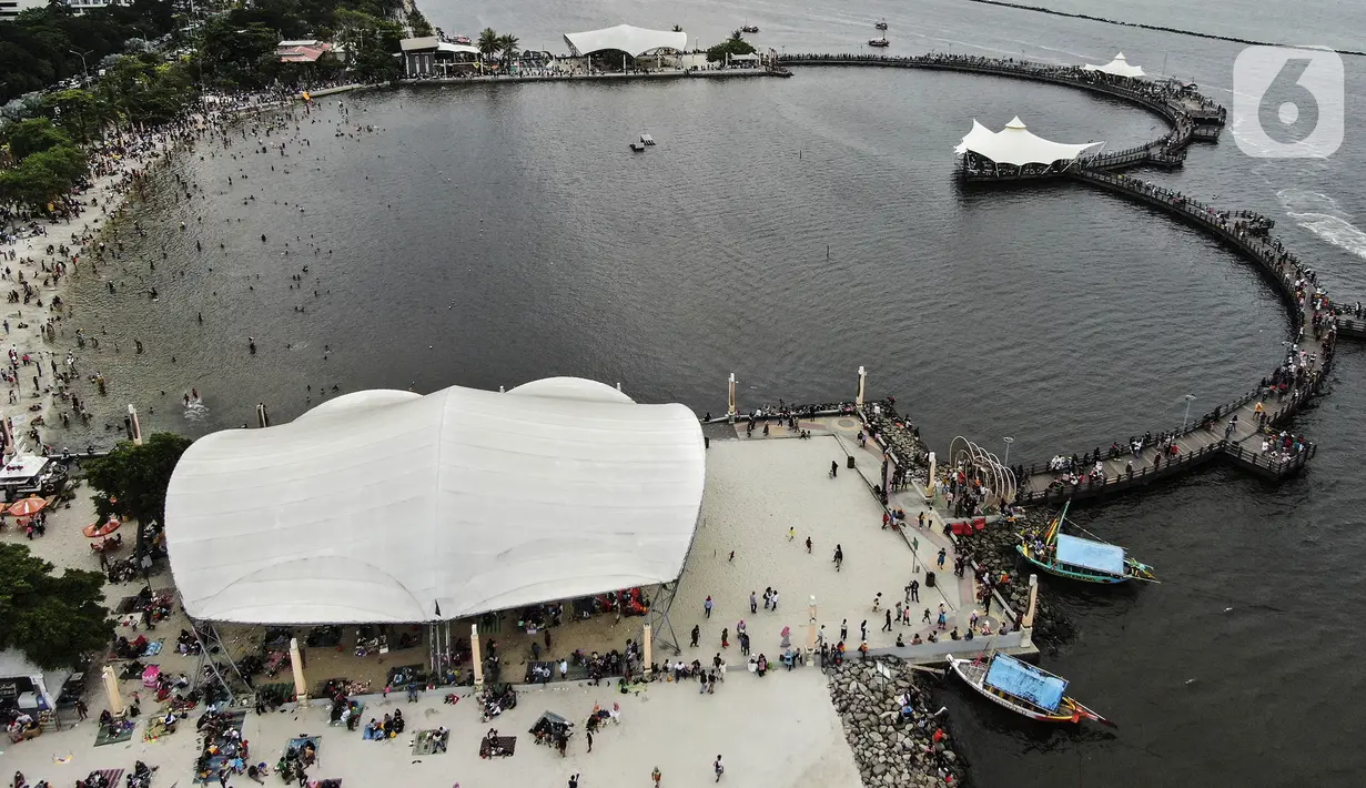 Foto udara menunjukkan keramaian pengunjung di Pantai Karnaval Ancol, Jakarta, Jumat (14/5/2021). Ancol dibuka khusus bagi warga ber-KTP DKI Jakarta dan membatasi jumlah wisatawan dengan kapasitas 30 persen. (Liputan6.com/Johan Tallo)