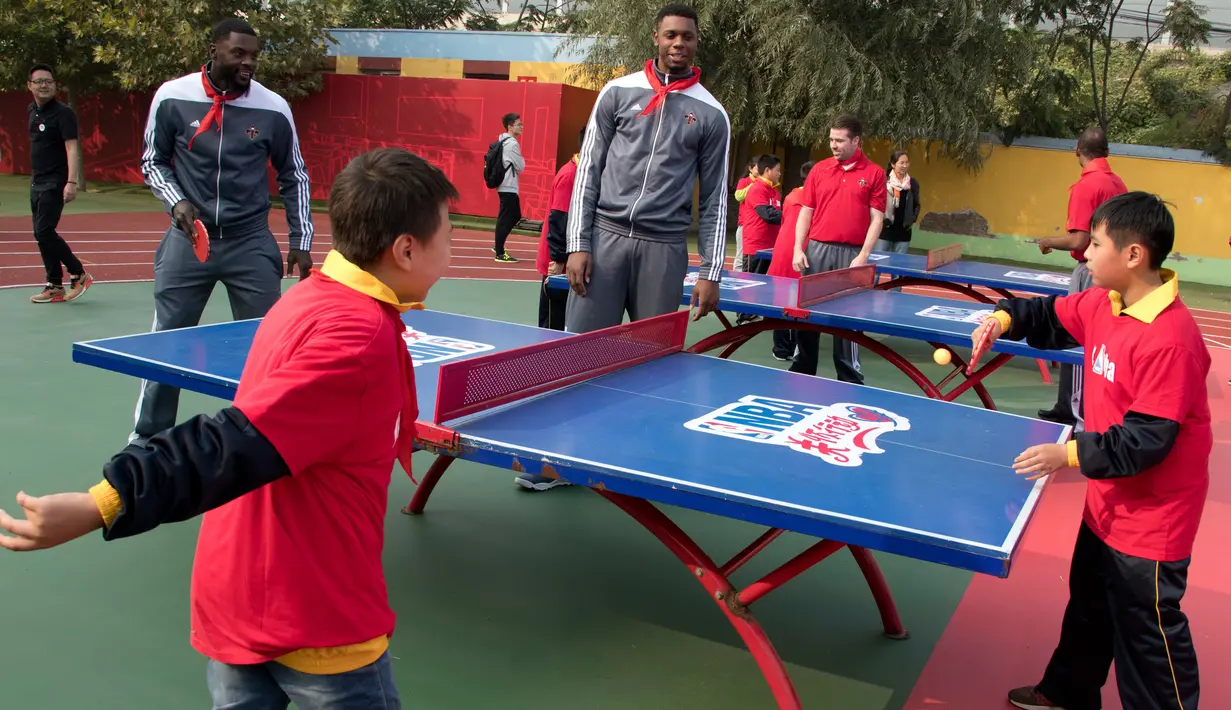Pemain New Orleans Pelicans, Lance Stephenson dan Terrence Jone bermain tenis meja dengan para siswa setalah NBA Cares Learn and Play Center di Sekolah Migran Huangzhuang, Beijing, Tiongkok (11/10). (AP Photo/Ng Han Guan)