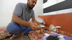 Warga Suriah, Hadheefa al-Shahadh membuat masker gas untuk menghadapi serangan pasukan pemerintah di Desa Maud Shurin, Provinsi Idlib, Selasa (11/). Masker dia buat dari gelas kertas, arang, kayu, kapas, plastik nilon, dan plester. (OMAR HAJ KADOUR/AFP)
