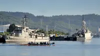 Lano cadik berlayar melewati kapal-kapal Angkatan Laut Indonesia di pangkalan angkatan laut di Banyuwangi, Provinsi Jawa Timur, Sabtu (24/4/2021). Militer melanjutkan operasi pencarian kapal selam KRI Nanggala 402 yang hilang pada 21 April saat latihan di lepas pantai Bali. (SONNY TUMBELAKA/AFP)