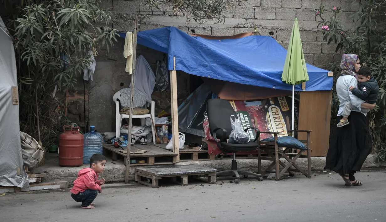 Seorang anak berada di dekat tenda di sebuah jalan di luar kamp pengungsi Eleonas di Athena (20/11/2019). Yunani akan menutup tiga kamp migran terbesarnya di pulau-pulau yang menghadap Turki, dan menggantinya dengan fasilitas baru yang lebih ketat untuk identifikasi, relokasi dan deportasi. (AFP/Lou